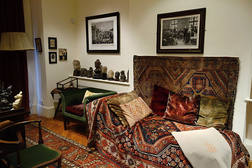 Sala de atendimento com divã e tapetes, em estilo clássico da psicanálise